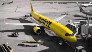 A yellow spirit airlines airplane at the gate.
